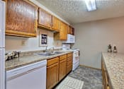 Thumbnail 6 of 20 - a kitchen with a sink and dishwasher and wooden cabinets. Fargo, ND Kennedy Apartments