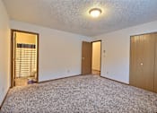 Thumbnail 9 of 20 - an empty living room with a closet and a door to a hallway. Fargo, ND Kennedy Apartments