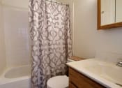 Thumbnail 17 of 18 - a bathroom with a shower curtain and a sink and a toilet. Fargo, ND Kingswood Apartments