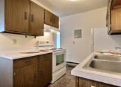 Thumbnail 13 of 18 - a kitchen with white appliances and wooden cabinets and a sink. Fargo, ND Kingswood Apartments