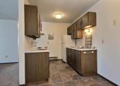 Thumbnail 12 of 18 - an empty kitchen with wooden cabinets and a refrigerator. Fargo, ND Kingswood Apartments