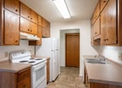 Thumbnail 16 of 25 - an empty kitchen with a stove refrigerator and sink. Fargo, ND Betty Ann Apartments