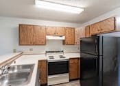 Thumbnail 16 of 19 - an empty kitchen with a stove refrigerator and sink. Fargo, ND Rosegate Apartments
