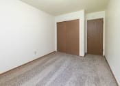 Thumbnail 21 of 34 - a room with a carpeted floor and a wooden door. Fargo, ND Islander Apartments