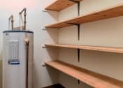 Thumbnail 11 of 12 - Grand Forks, ND Madison Apartments. A closet with multiple shelves and a water heater.