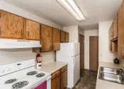 Thumbnail 7 of 20 - Grand Forks, ND Library Lane Apartments. A kitchen with a white refrigerator freezer next to a stove top oven