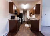 Thumbnail 10 of 20 - Grand Forks, ND Library Lane Apartments a kitchen with brown cabinets and a wood floor