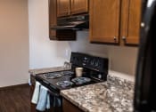 Thumbnail 11 of 20 - Grand Forks, ND Library Lane Apartments a kitchen with granite countertops and a black stove top oven