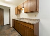 Thumbnail 16 of 20 - a kitchen with a sink and cabinets and a door to a hallway .Fargo, ND Maplewood Bend Apartments