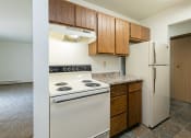 Thumbnail 15 of 20 - a kitchen with white appliances and wooden cabinets and a refrigerator. Fargo, ND Maplewood Bend Apartments