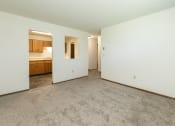 Thumbnail 7 of 20 - an empty living room and kitchen with white walls and carpet. Fargo, ND Maplewood Bend Apartments