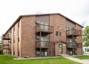Thumbnail 19 of 20 - a brick apartment building with balconies and a bike parked outside. Fargo, ND Maplewood Bend Apartments