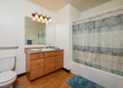 Thumbnail 15 of 17 - a bathroom with a toilet sink and mirror and a shower. Fargo, ND Maybrook Apartments