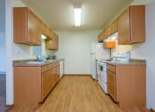 Thumbnail 10 of 17 - an empty kitchen with wooden cabinets and white appliances. Fargo, ND Maybrook Apartments
