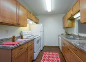 Thumbnail 7 of 17 - a kitchen with wood cabinets and white appliances and granite counter tops. Fargo, ND Maybrook Apartments