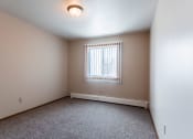 Thumbnail 9 of 16 - Grand Forks, ND Mayfair Apartments a bedroom with a window and carpeted floors