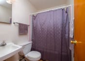 Thumbnail 8 of 15 - a bathroom with a purple shower curtain and a toilet and sink. Fargo, ND Morningside Apartments