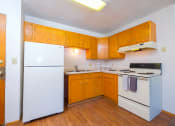 Thumbnail 6 of 15 - an empty kitchen with white appliances and wooden cabinets. Fargo, ND Morningside Apartments