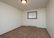 Thumbnail 23 of 26 - a bedroom with carpeted floors and a window. Fargo, ND Monticello Apartments