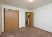 Thumbnail 24 of 26 - a bedroom with a carpeted floor and a door to a closet. Fargo, ND Monticello Apartments