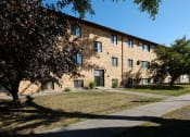 Thumbnail 26 of 26 - a brick building with a sidewalk and trees in front of it. Fargo, ND Monticello Apartments