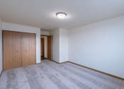 Thumbnail 13 of 16 - a bedroom with carpet and a door to a hallway. Moorhead, MN South Park Apartments