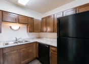 Thumbnail 10 of 16 - full kitchen with black refrigerator and sink at the reserve at walnut creek apartments. Moorhead, MN South Park Apartments