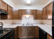 Thumbnail 9 of 16 - an empty kitchen with wooden cabinets and granite counter tops. Moorhead, MN South Park Apartments