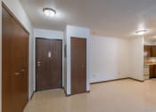 Thumbnail 8 of 16 - an entry door with a couple closets and a dining room and kitchen in the background. Moorhead, MN South Park Apartment