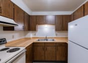 Thumbnail 7 of 16 - an empty kitchen with white appliances and wooden cabinets. Moorhead, MN South Park Apartments