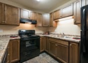 Thumbnail 6 of 10 - a kitchen with black appliances and white countertops. Bismarck, ND Newgate Apartments
