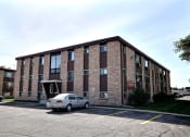Thumbnail 16 of 16 - a brick apartment building with a car parked outside. Fargo, ND North Manor Apartments