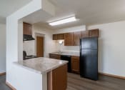 Thumbnail 12 of 16 - an empty kitchen with a counter top and a black refrigerator. Fargo, ND North Manor Apartments
