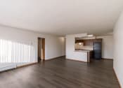 Thumbnail 10 of 16 - the living room and kitchen of an empty apartment with wood floors and white walls. Fargo, ND North Manor Apartments