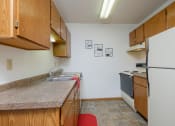 Thumbnail 7 of 11 - Kitchen with wooden cabinets and a sink and a refrigerator, Oak Court Apartments, Fargo 