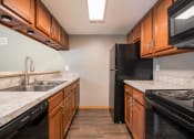 Thumbnail 10 of 21 - Omaha, NE Beacon Hill Apartments. A kitchen with wood cabinets and marble countertops