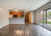Thumbnail 9 of 21 - Omaha, NE Beacon Hill Apartments. A living room with a glass sliding door and a kitchen in the background