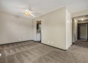 Thumbnail 14 of 21 - Omaha, NE Beacon Hill Apartments. An empty living room with a ceiling fan and a kitchen in the background