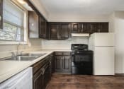 Thumbnail 13 of 21 - Omaha, NE Beacon Hill Apartments. A kitchen with dark wood cabinets and white appliances