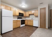 Thumbnail 4 of 10 - Omaha, NE Deerfield Apartments. A kitchen with white appliances and wooden cabinets