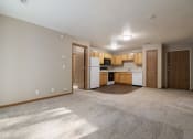 Thumbnail 5 of 10 - Omaha, NE Deerfield Apartments an empty living room with a kitchen in the background