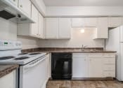 Thumbnail 11 of 34 - Omaha, NE Evergreen Terrace Apartments. A kitchen with white cabinets and black appliances