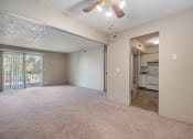 Thumbnail 9 of 34 - Omaha, NE Evergreen Terrace Apartments. A living room with a ceiling fan and a kitchen in the background