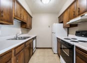Thumbnail 18 of 23 - Omaha, NE Maple Ridge Apartment. A kitchen with white countertops and wooden cabinets
