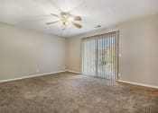 Thumbnail 15 of 23 - Omaha, NE Maple Ridge Apartments. A bedroom with a ceiling fan and a sliding glass door