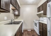 Thumbnail 9 of 29 - Omaha, NE Stony Brook Townhomes. A kitchen with white appliances and dark wood cabinets