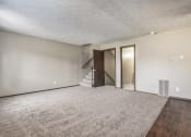 Thumbnail 7 of 29 - Omaha, NE Stony Brook Townhomes. a living room with a carpeted floor and a staircase in the background
