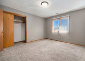 Thumbnail 11 of 27 - Omaha, NE Woodland Pines Apartment. A bedroom with a large window and a door to a closet