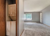 Thumbnail 9 of 27 - Omaha, NE Woodland Pines Apartments. A living room with a laundry closet with a washer and dryer in it.