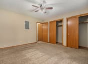 Thumbnail 17 of 27 - Omaha, NE Woodland Pines Apartments. A bedroom with a ceiling fan and two closets